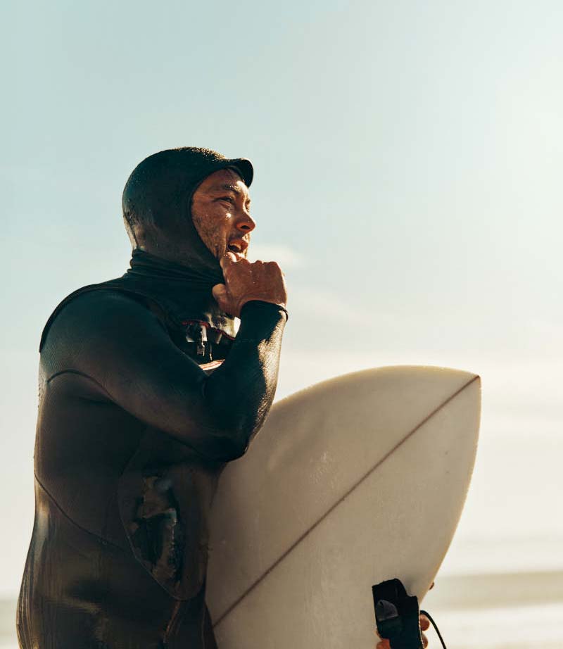 Aaron Jackson in a wetsuit holding a surfboard